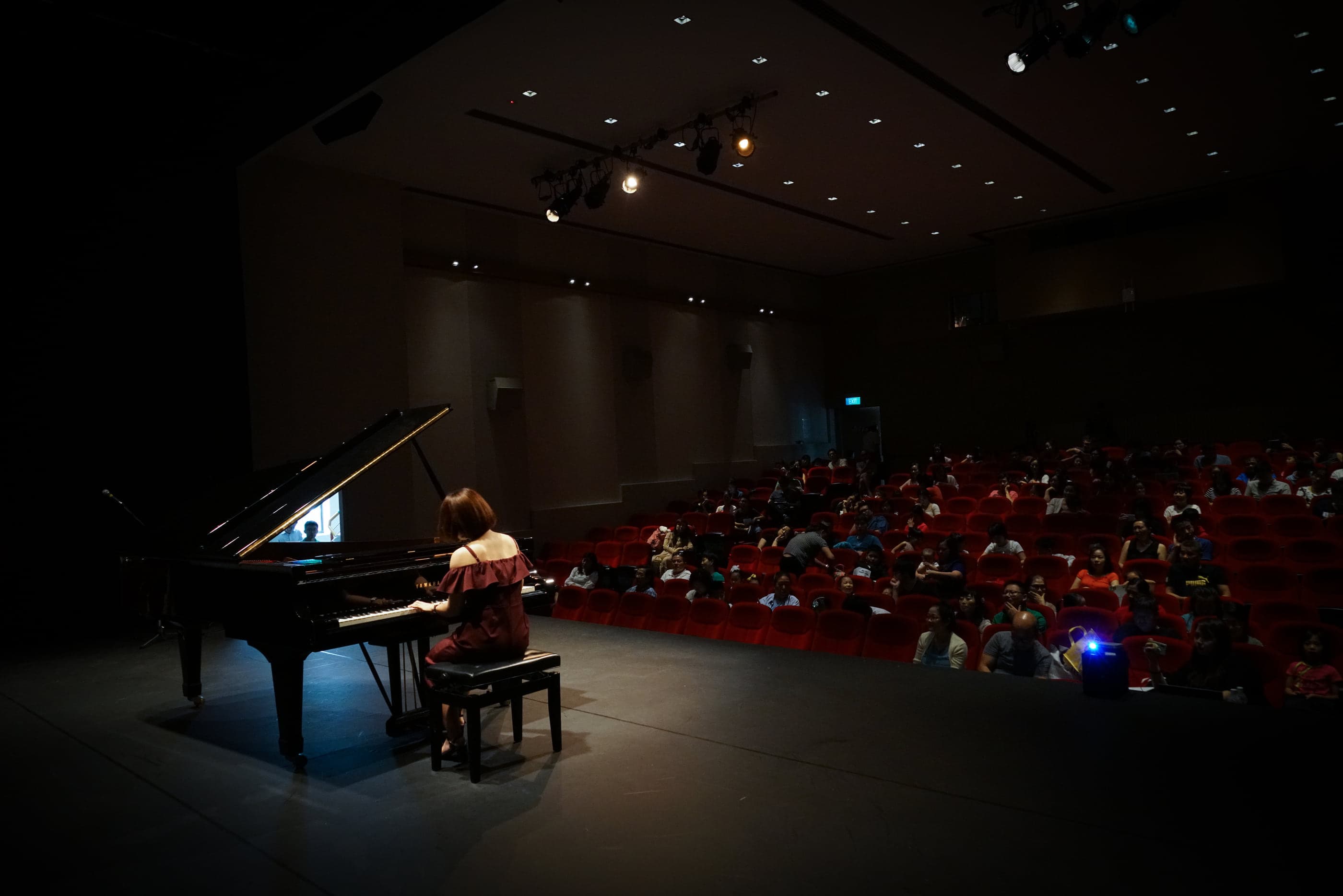 Kathrine Leong at the grand piano on a concert hall stage, playing to a full audience