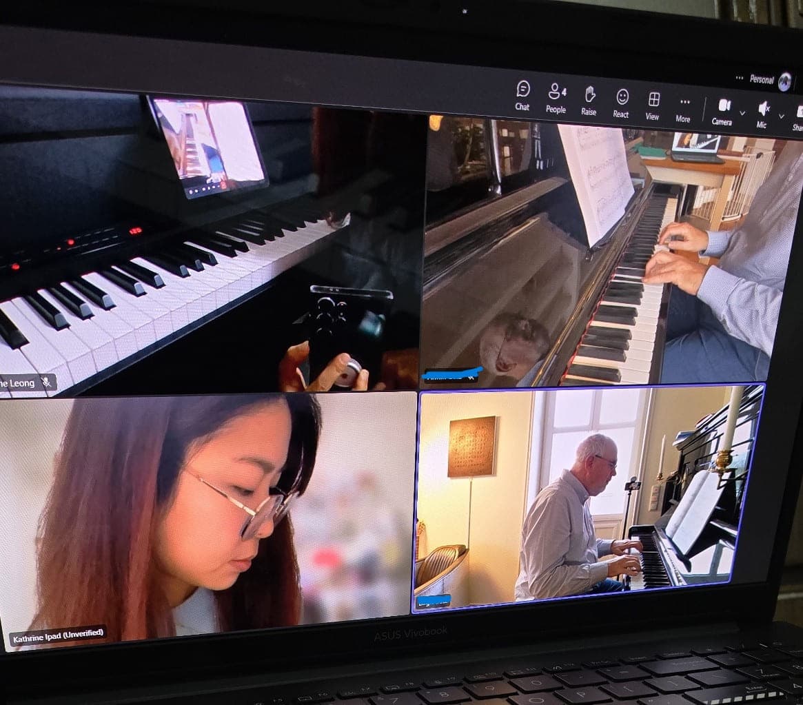 An online piano lesson on a laptop, with the keyboard and both players in view