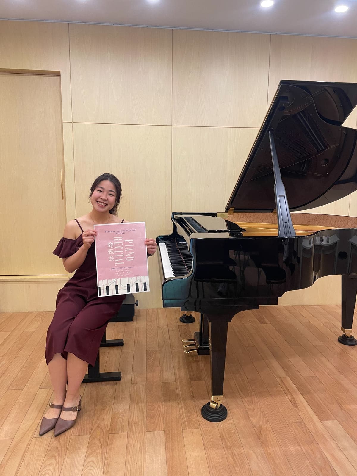 Kathrine Leong holding the recital programme beside the concert grand
