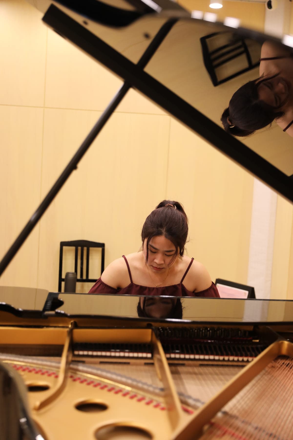 Kathrine Leong playing, seen through the open lid of the concert grand